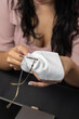 © Alejandro - A concentrated woman uses a cloth to clean her eyeglass lenses while seated in a workspace.