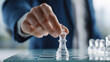 © kun - Closeup of businessman hand holding glass chess piece making strategic move, representing corporate business strategy, leadership success, planning, competition and management decision making concepts