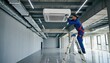 © Lightning - HVAC technician installing a new air conditioning unit on a ladder in a large empty commercial space