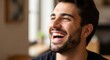 © MSTKolpana - A man laughing heartily while sitting in a cozy living room setting.