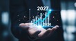 © mlangsen - Upward graph showing growth from 2026 to 2027 held in hand