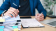 © Smile Studio AP - Business professional reviewing and organizing stack of documents with laptop. Concept of paperwork management, administrative workload, compliance, audit process, and office documentation.