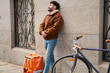 © Oscar - Male courier resting leaning on wall with delivery bag and bicycle
