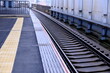 © taka - 駅のホームと線路、安全を支える黄色の点字ブロックが続く風景（公共交通機関・バリアフリー）