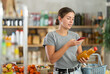 © JackF - Young woman buyer scanning qr code for fresh peach juice in bottle in grocery store
