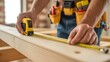 © Desmon - Close up of builder's hands using a yellow measuring tape on a wooden surface