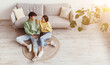 © Prostock-studio - Stay home leisure concept. Top view of happy young Asian couple relaxing with digital tablet at home, sitting on floor, watching videos together or browsing internet, free space