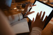 © Studio Marmellata - A person's hands interact with a tablet displaying financial charts and data, with a notebook and pen nearby, suggesting analysis and planning.