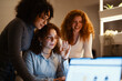 © Studio Marmellata - Three young women collaborate on a project, one raising her hand as if to speak during a video call.