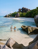 Stunning couple walks hand in hand along the serene Anse Source d'Argent beach in Seychelles