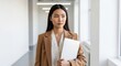 © Running opossum - focused professional asian woman holding laptop walking in modern office corridor