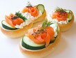 Three gourmet bread rolls topped with smoked salmon, cucumber slices, and fresh dill, arranged on a white background for a culinary presentation