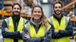 © Babb - Smiling warehouse team in safety vests caucasian female and males, young adults in industrial setting.