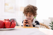 © New Africa - Little boy drinking fresh pomegranate juice at table indoors