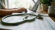 © NRD - stethoscope, medical, report, laptop, healthcare, research, data. Close-up of green stethoscope on medical journals and reports with a doctor working on a laptop in the background.