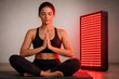 © Maryia - LED panel beauty light therapy session shows young woman meditating beside red light device, modern wellness treatment concept, relaxation skincare technology, commercial health lifestyle, copyspace
