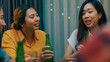 © tirachard - Group of multiethnic adult Asia friend drink alcohol beer bottle glass and fun talk laugh enjoy hangout party at dining table in night life indoor home. Happy hour millennial generation inside house.