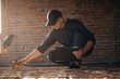 © standret - Sitting and using leveling tool. Builder is working on construction site, unfinished building