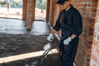 © standret - Holding the device for leveling the floor, concrete. Builder is working on construction site, unfinished building