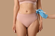 © Pixel-Shot - Plastic surgeon marking woman's belly on beige background, closeup