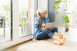 © Westend61 - Mature woman listening to music while working on digital tablet