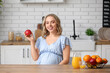 © Pixel-Shot - Young pregnant woman with apple at table in kitchen