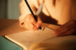 © Johnér - Sunlight shining on hand of businesswoman writing in diary with pencil at office