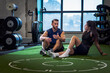 © Johnér - Male coach talking with woman while sitting on floor in gym