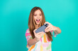 © deagreez - Joyful young woman taking a playful selfie against a vibrant teal background, capturing happiness, style, and trendy vibes