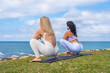 © unai - Women practicing yoga and meditating outdoors overlooking ocean