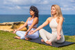 © unai - Women practicing yoga and meditation by ocean relaxing