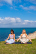 © unai - Women practicing yoga and meditation by ocean coastline