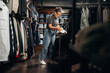 © standret - Female retail worker in casual attire organizes clothing items on a table inside a clothing store, shelves filled with folded jeans in the background