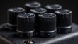 © Tan - Detailed close-up of a stack of black guitar amplifier control knobs with intricate textured surfaces