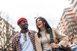 © unai - Happy multiracial couple smiling walking together in city street