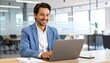 © isrofil - Smiling Businessman Working on Laptop in Modern Office Setting.