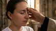 © AlfaSmart - Woman participates in anointing during a religious ceremony. Sacrament of anointing of sick for spiritual healing, faith and prayer concept.