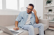 © SHOTPRIME STUDIO - Engaged man working remotely at home, wearing headphones, with a laptop. Bright and cozy interior, showcasing a modern lifestyle and digital nomad vibes.