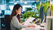 © Yaroslav Stepannikov - Young Asian woman adjusting documents while seated at modern workstation, professional yet relaxed posture, clean corporate lifestyle photography