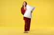 © New Africa - Happy woman in stylish pyjamas with pillow on yellow background