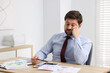 © New Africa - Unhappy businessman feeling fatigue at wooden table in office