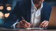 © estrel - a businessman is using his laptop and holding an apple pencil closeup on the hand with a white sleeveless shirt and navy blue suit jacket focused look at the screen