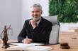 © New Africa - Portrait of smiling notary in suit with pen at table in office