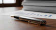 © Robert Garcia - Close-up of a stylish pen resting on a desk with a stack of paper and a chart