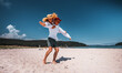 © Aboltin - Carefree young couple playing on sandy beach. Woman joyfully poses midair on man's back, both laughing and enjoying romantic summer moment surrounded by sky, sun, and ocean.