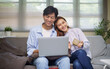 © matinee - Happy couple relaxing on a couch while using a laptop. Technology, and everyday life concept.