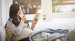 © Hinrichsen/peopleimages.com - Asian, pregnant woman and reading book with fruit in home for maternity, guidance and nutrition. Person, snack and pregnancy novel for prenatal tips, childbirth information and motherhood in lounge