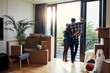 © BuyoutReese09/peopleimages.com - Glass door, boxes and couple with hug in new home for moving in, mortgage success and balcony view. Support, back of people or embrace in house for relocation, real property ownership and achievement