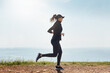 © peopleimages.com - Woman, running and fitness on road by ocean, outdoor or endurance training with space for wellness. Person, runner and exercise in nature with workout, seaside and speed at beach for cardio benefits