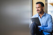 © Westend61 - Smiling businessman sitting at the window using tablet